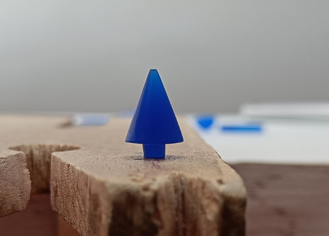 Close up of a bench peg with a small christmas tree out of blue wax on top