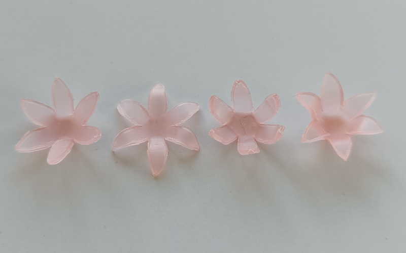 4 pink sheet wax flowers in a row all a little bit different from each other. Petals slightly bend up, slightly bend up and back, bend up a lot, bend up a lot and back 