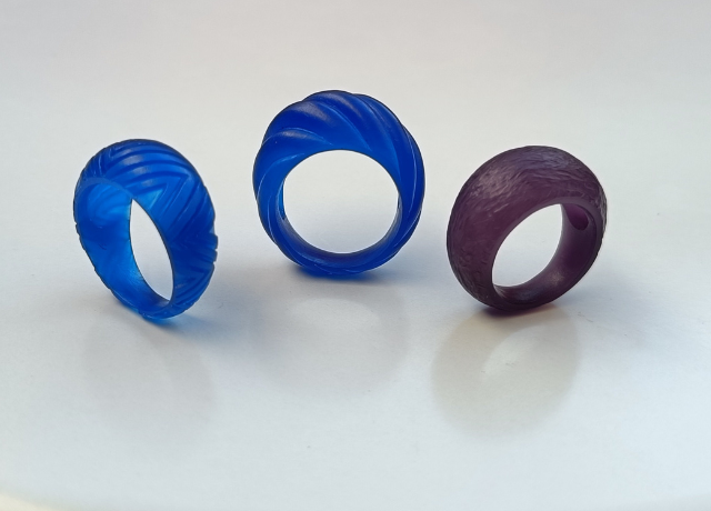 3 bombe rings side by side, left blue wax with a carved out triangular pattern, middle blue wax with a wave pattern, left purple wax with a scratchy texture