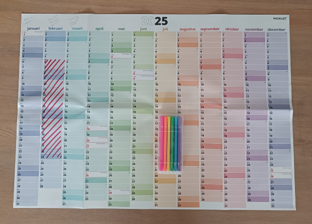 2025 wall calendar for 2025 with a few things marked already and a set of markers on top of the calendar