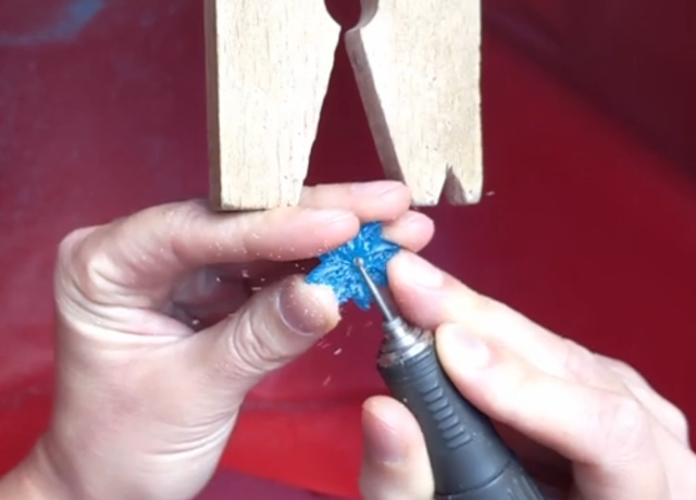 Close up shot of hands working at the bench: burring a piece of turquoise wax