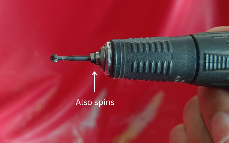 Close up of hand piece of a micromotor with an arrow pointing to the chuck