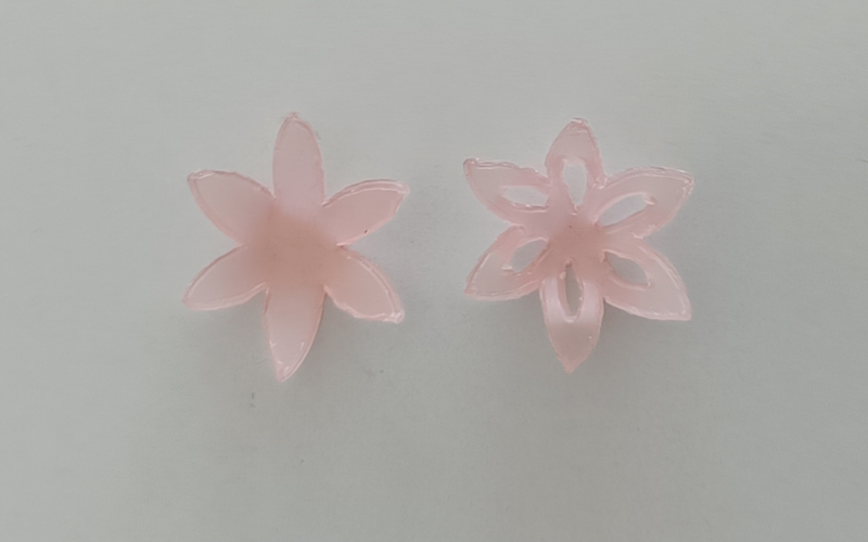 2 pink sheet wax flowers side by side with petals gently folded up. Left flower is solid, right one has cutouts on the petals