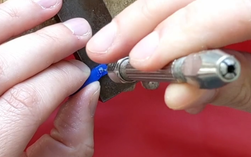 Close up of hands drilling through a piece of blue wax