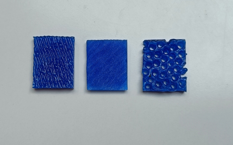 Close up of 3 small pieces of blue wax with different surface textures on top