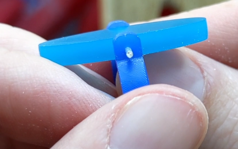 Close up of hands holding a thing blue wax ring with a piece of turquoise wax suspended horizontally in the middle