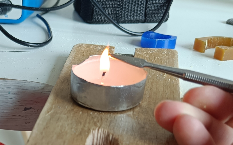 Close up of tea light on a bench peg and a carving tool being heated in the flame