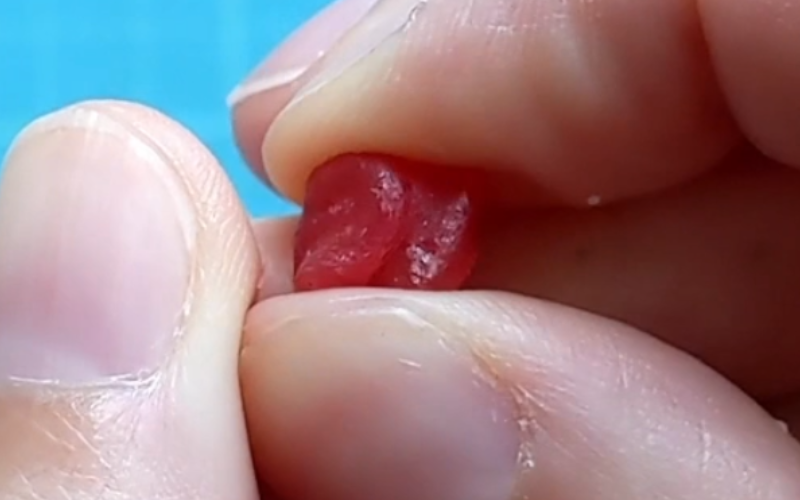 Close up of fingertips kneading a small piece of red wax