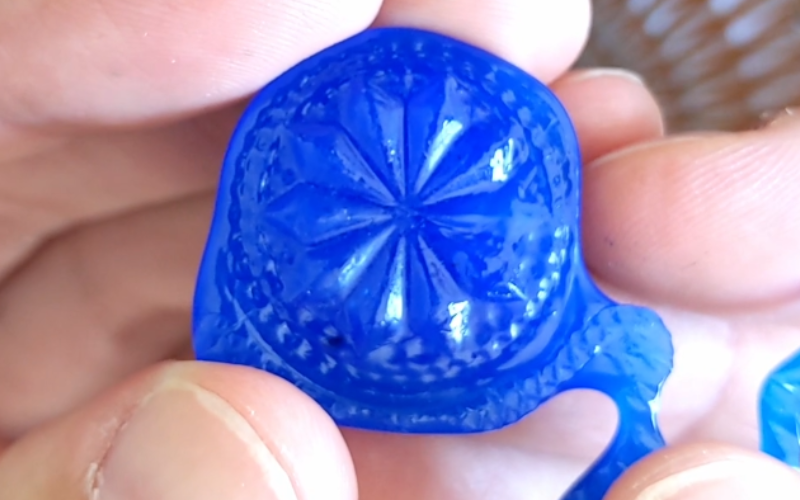 Close up of hands holding blue hard wax imprint of what was poured in previous photo