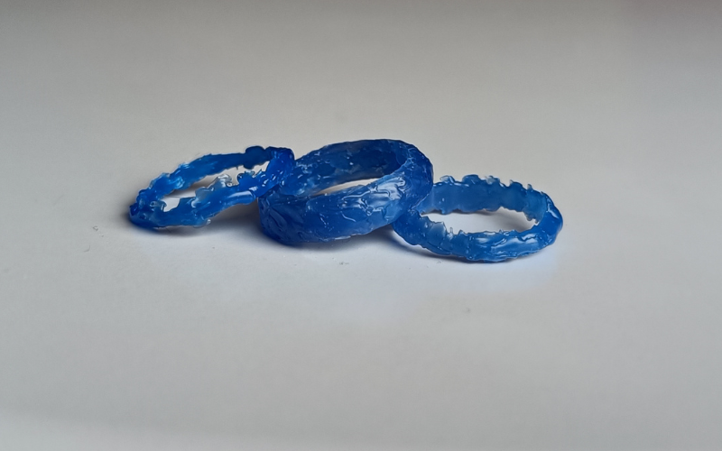 3 rings from blue wax partially stacked on top of each other with melted looking surfaces