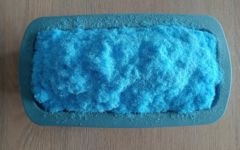 Close up of a cake mold filled completely with blue wax dust