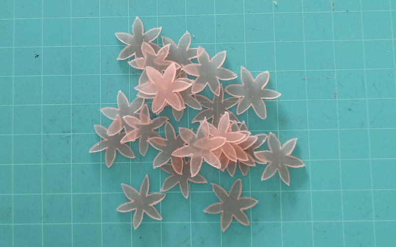 cutting mat with a pile of 6 petal pink wax flowers