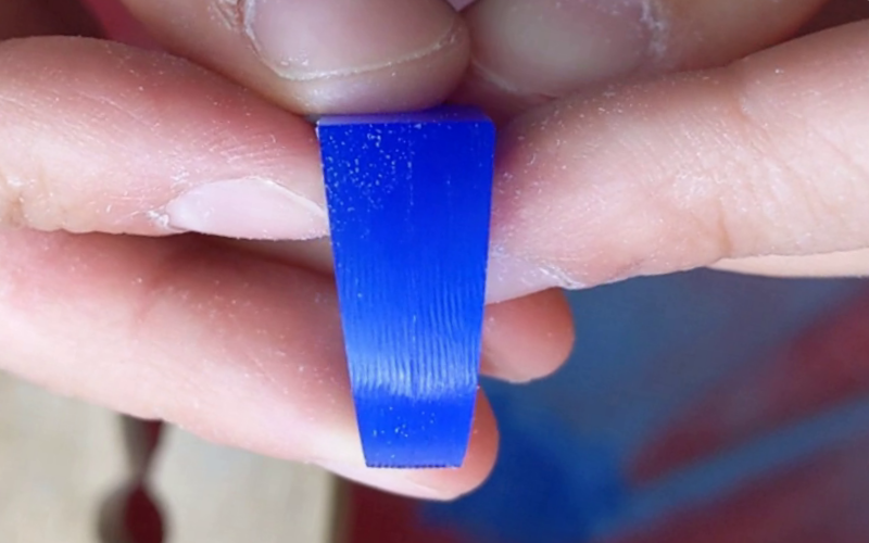 close up of hands holding a blue wax ring, the surface of the ring is rough