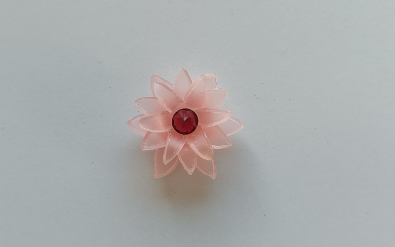 pink sheet wax flower from triple layer, and upside down red gemstone is placed in the center