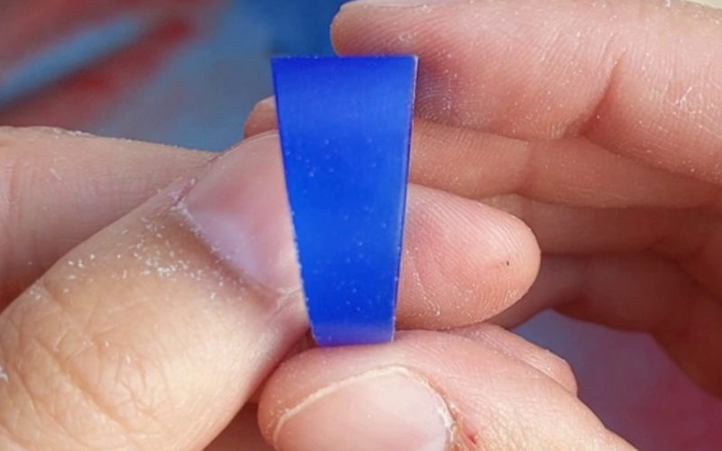 close up of hands holding a blue wax ring, the surface of the ring is smooth